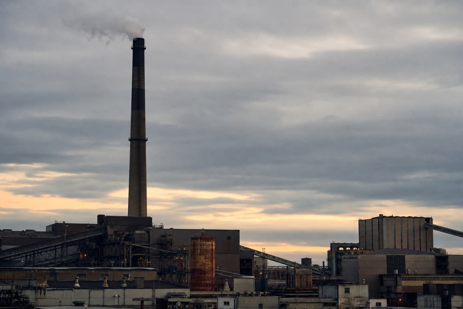 Industrieschornstein mit Emissionen vor bewölktem Himmel